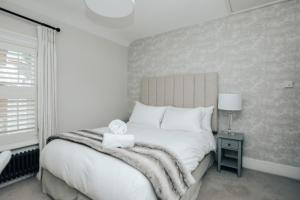 ein Schlafzimmer mit einem großen weißen Bett und einem Fenster in der Unterkunft The Dragonfly - Central 2 bedroom house in Henley on Thames
