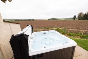 una bañera de hidromasaje al lado de una casa junto a un campo en Bachilton Farm Holidays, en Perth