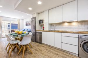 een keuken met witte kasten en een tafel en stoelen bij Fuengirola center, 3 bedrooms, and parking in Fuengirola