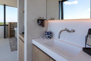a white kitchen with a sink and a window at Duinhotel Tien Torens in Zoutelande