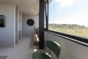 a room with two green chairs and a window at Duinhotel Tien Torens in Zoutelande