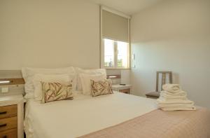 una camera da letto con un letto bianco con cuscini e una finestra di Flor de Valença Guest House a Valença