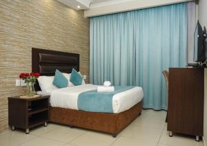 1 dormitorio con 1 cama con cortinas azules y TV en Bayside Hotel Pietermaritzburg en Pietermaritzburg