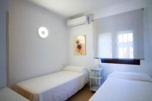 a white room with two beds and a window at Apartamentos Turisticos Trajano in Bolonia