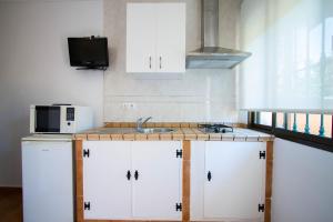 a kitchen with white cabinets and a sink and a microwave at Apartamentos Turisticos Trajano in Bolonia