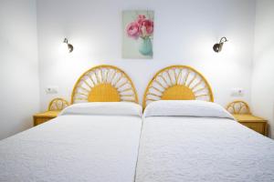 two beds with white sheets and a vase of flowers at Apartamentos Turisticos Trajano in Bolonia