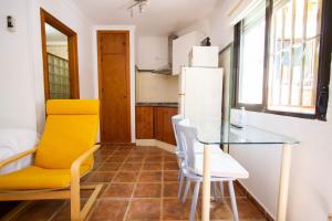 a kitchen with a glass table and a yellow chair at Apartamentos Turisticos Trajano in Bolonia