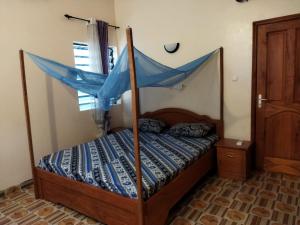 1 dormitorio con cama con dosel y edredón azul en Bethel House 2 Villas, en Abomey-Calavi
