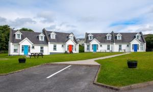 una fila de casas blancas con puertas azules y un estacionamiento en Dingle Holiday Homes en Dingle