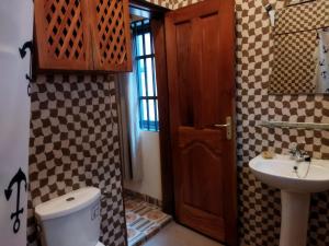 een badkamer met een wastafel, een toilet en een deur bij Bethel House 2 Villas in Abomey-Calavi