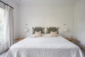 1 dormitorio con 1 cama blanca grande y 2 almohadas en Divina casa con parque pileta en mini barrio cerrado. en Del Viso