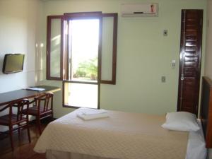 1 dormitorio con cama, escritorio y ventana en Casa do Professor Visitante Unicamp, en Campinas