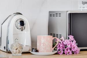 a kitchen counter with a toaster and a mug and flowers at ARI GREEN Apartment near Atrium Mall in Arad