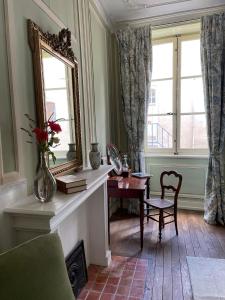 uma sala de estar com um espelho, uma mesa e uma cadeira em Maison Zola em Saint-Amand-Montrond