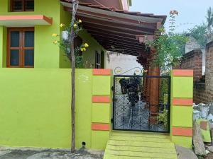 una casa verde con una puerta negra en Abhi Homestay Hampi en Hampi