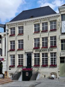 un edificio de piedra con un cartel en la parte delantera en Hotel Restaurant Steenhuyse en Oudenaarde