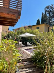 een zwembad met een parasol, stoelen en planten bij Villa Arzilla in Desenzano del Garda
