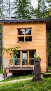 a wooden house with a porch and a tree at Forest Chalet Resort FELIZITAS in San Felice