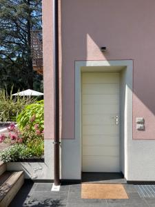 una porta bianca su un edificio rosa con fiori di Villa Arzilla a Desenzano del Garda
