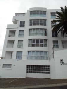 un edificio bianco con una palma di fronte di Palmsbeach 3 a Strand