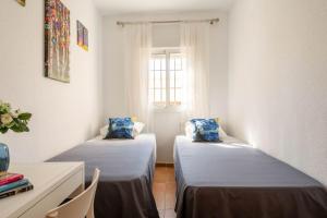 two twin beds in a room with a window at Apartamento centro Rota. 2 minutos de la playa.. in Rota