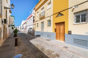 an empty street with buildings and a wooden door at Apartamento centro Rota. 2 minutos de la playa.. in Rota