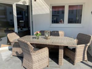 una mesa con sillas de mimbre y una mesa con reloj. en Villa Mare Meerblick, en Glücksburg