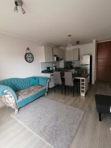 a living room with a blue couch and a kitchen at Departamento en La Serena in La Serena