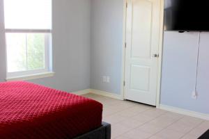 1 dormitorio con cama roja y ventana en Spacious Home, Short Walk to Beach, Heated Pool! en Corpus Christi
