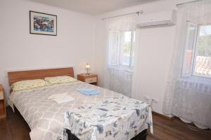 a bedroom with a bed and two windows at Apartman Anamarija Valun II in Valun