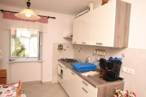 a kitchen with white cabinets and a stove top oven at Apartman Anamarija Valun II in Valun +6 photos