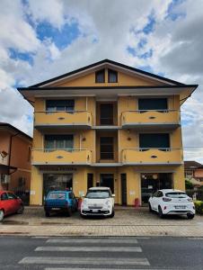 un bâtiment jaune avec des voitures garées devant lui dans l'établissement Appartamento incantevole a Massarosa tra Viareggio e Lucca, à Massarosa