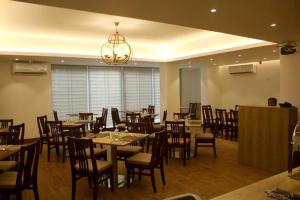 a dining room with tables and chairs and a chandelier at Priyo Nibash Stylish Residential Hotel in Dhaka
