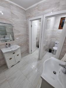 a white bathroom with a sink and a toilet at Pensiunea Sofia in Onceşti +11 photos