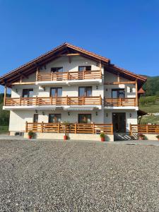 a large white building with wooden balconies and a roof at Pensiunea Sofia in Onceşti