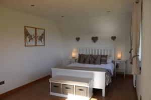 1 dormitorio con 1 cama blanca grande y 2 mesas en The Cottage - spacious getaway with stunning views, en Auchenblae