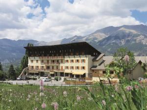 a large building with mountains in the background at Hôtel Soleil des Neiges in Le Sauze
