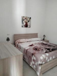 1 dormitorio con 1 cama, 2 mesas y una foto en la pared en CASA RED ROSE, en Maddaloni
