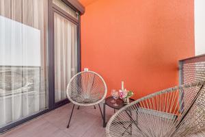 een balkon met 2 stoelen en een tafel met wijnglazen bij ARI Turquoise Apartment in ARED in Arad