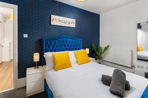 a blue bedroom with a large bed with yellow pillows at FLATZY - Lovely Sefton Park Retreat in Liverpool