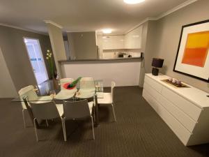 een eetkamer met een glazen tafel en witte stoelen bij 2 Bed 2 Bath Apartment in Braddon, Canberra - Pool, Gym and Free Parking in Canberra