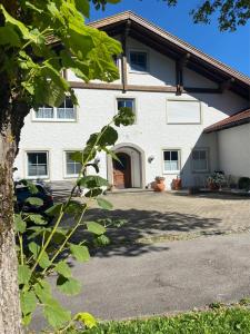 uma grande casa branca com uma entrada em Heike & Günther Ferienwohnung em Seeg