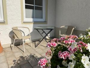 um pátio com duas cadeiras, uma mesa e flores em Heike & Günther Ferienwohnung em Seeg