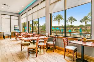 un restaurante con mesas y sillas y vistas a la piscina en Modern Retreat at Regal Oaks Resort, en Orlando
