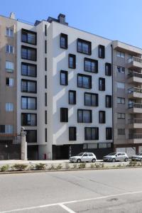 a large white building with cars parked in front of it at HM - ISSY Oporto Apartment in Porto