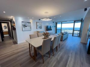 a dining room and living room with a table and chairs at Luxo e Vista Mar Maravilhosa na Barra da Tijuca B11-0013 in Rio de Janeiro