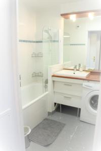 biała łazienka z umywalką i pralką w obiekcie Logement familial tout équipé (1 station de Paris) w mieście Saint-Denis