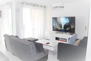 サン・ドニにあるLogement familial tout équipé (1 station de Paris)の白いリビングルーム(椅子2脚、テレビ付)