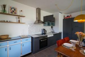 une cuisine avec des placards bleus et une table en bois dans l'établissement The Azalea beautiful quiet apartment for 4 people!, à Doussard