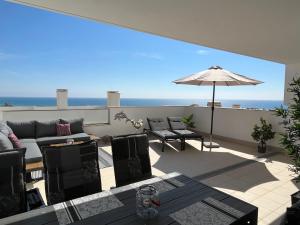 a patio with a couch and an umbrella and the ocean at Lovely New Luxery Beach Apartment in Mojacar Playa in Mojácar